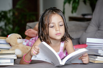 Pausa para Imaginar Criança deitada Entre Contos e Fábulas lendo livros no sofá.