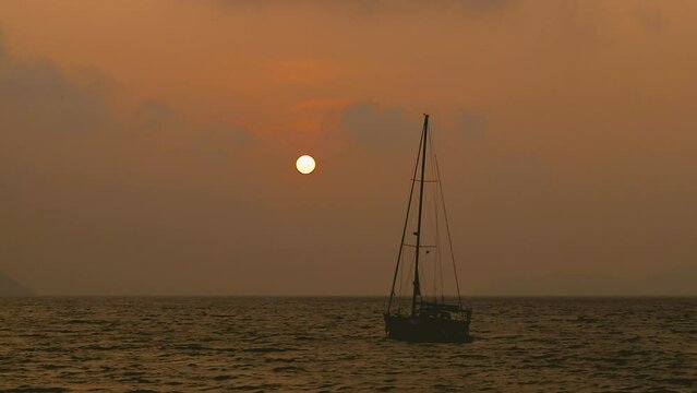 February 1, 2024 - Rawai, Phuket Thailand. Time lapse taken from the landing pier out into the bay while the sun comes up behind anchored sailboats.