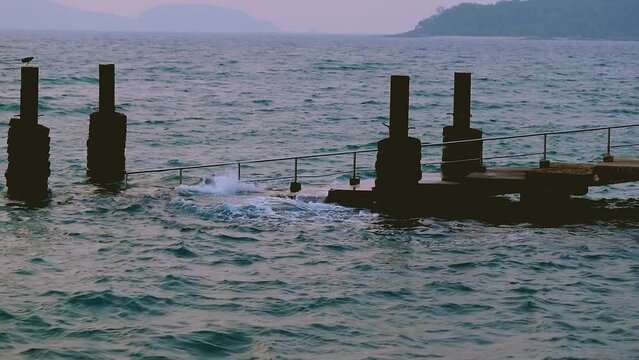 February 1, 2024 - Rawai, Phuket Thailand. Slow motion of small waves gently crashing into the landing pier steps in early morning.