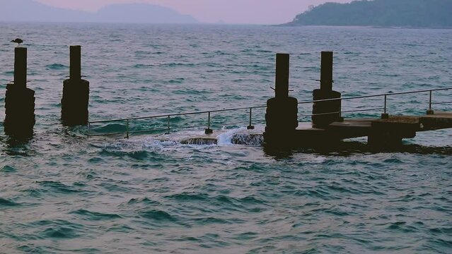 February 1, 2024 - Rawai, Phuket Thailand. Small waves gently crashing into the landing pier steps in early morning.