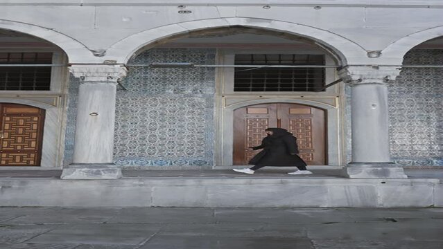 A woman in black exploring the historical topkapi palace's intricate architecture and islamic tilework in istanbul.