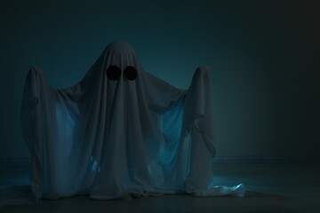 Creepy ghost. Woman covered with sheet on dark background, space for text