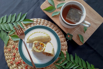 Pastel Goreng. Peranakan snack of fried puff pastry with a filling of sauteed skipjack smoked fish. Served in a  plate garnished with cayenne and  rustic tea set.
