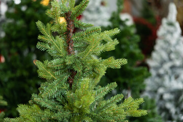 Many artificial Christmas trees on market. Green artificial fir trees for sale