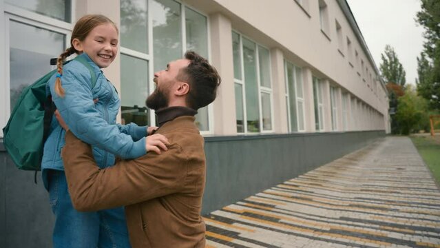 Daughter running to father. Happy family man lift girl primary school outside after lessons educational hug embrace cuddle candid childcare parenting relationship love emotions greeting meet together