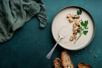 Potato and cauliflower soup served in two green bowls garnished with croutons and parsley....