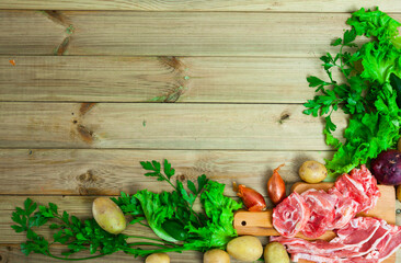 Fresh slices of lamb and vegetables assortment on natural wooden desk, top view