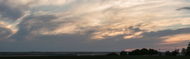 A landscape with an enchanting sunset. Panorama. Tragic gloomy sky. The last flashes of the sun on...