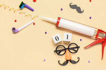Funny glasses with construction adhesive and party decor on beige background. April Fools Day