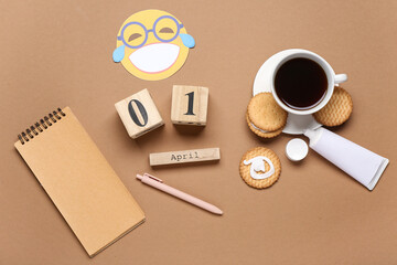 Cookies with toothpaste, calendar and cup of tea on brown background. April Fools Day prank