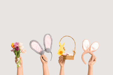 Female hands holding Easter bunny ears headbands with basket and tulips on white background