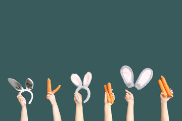 Female hands holding Easter bunny ears headbands and carrots on dark green background