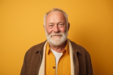 Portrait of a senior man with a white beard on a yellow background.