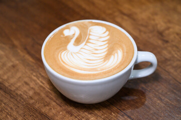 Artistic latte swan design on wooden table
