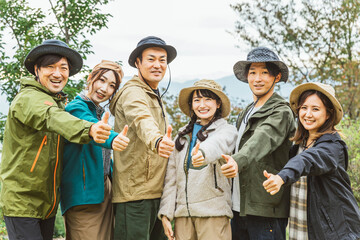 グーサインを出すアウトドアファッションの男女（キャンプ・登山・観光・環境）
