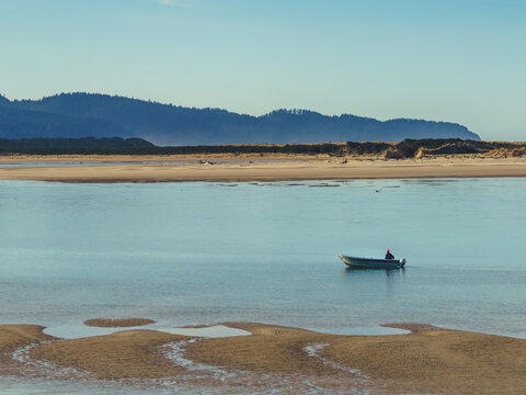 small boat navigates an empty Pacific coast bay on a chilly morning