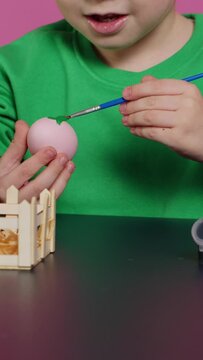 Vertical Video Young adorable kids coloring easter eggs with watercolor paint, creating lovely designs to celebrate spring holiday. Cheerful brother and sister painting festive decorations in studio