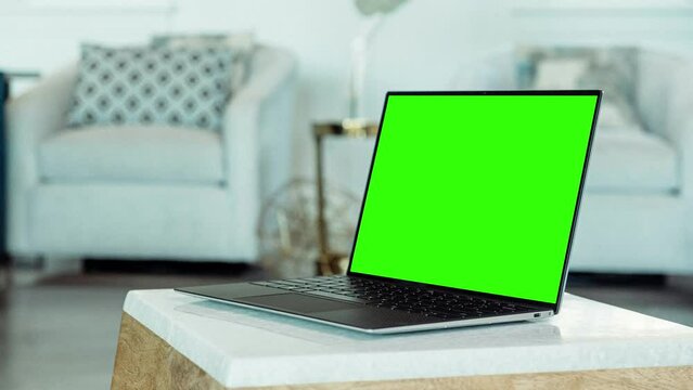 Laptop Computer with Mock Up Green Screen Display Standing on the Table in Cozy Living Room.