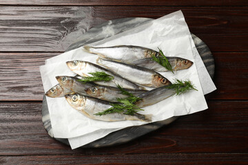 Fresh raw sprats and dill on wooden table, top view