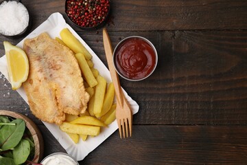 Delicious fish and chips served on wooden table, flat lay. Space for text