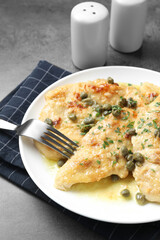 Delicious chicken piccata with herbs served on grey table