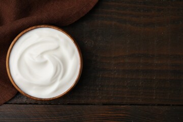 Delicious natural yogurt in bowl on wooden table, top view. Space for text