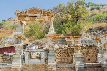 Ornately carved archaeological remains under a blue sky with fluted columns, in Ephesus, Turkiye
