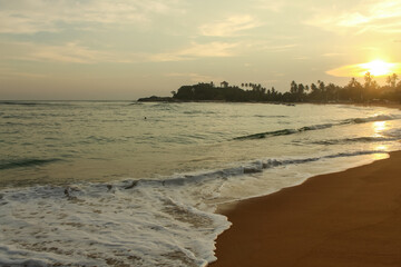 Obraz premium Beach with golden sand and blue ocean water on most popular Unawatuna