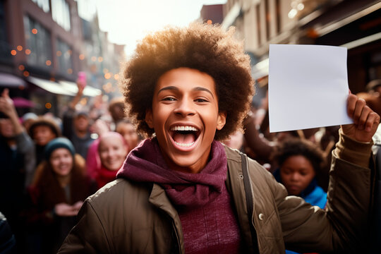 A young black man with a white piece of paper in his hand is smiling in a street parade