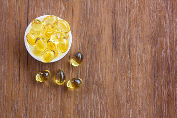 Cod liver oil omega 3 gel capsules on wooden background