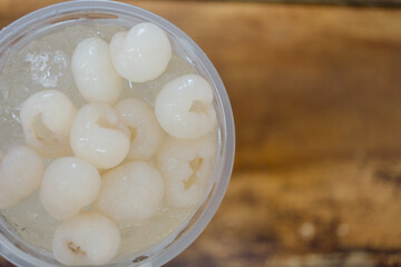 Longan juice in a clear plastic glass with wood brown background