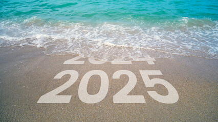 The waves erase 2024 to 2025 written in the sand by the beach. 2025.