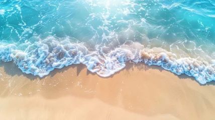 Fotobehang An abstract sandy beach seen from above, with clear blue water waves and sunlight, representing a summer vacation background concept for banners. © wpw