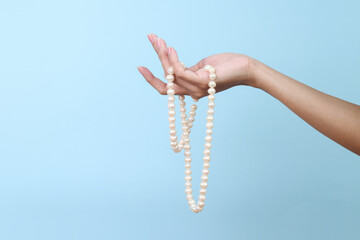 Woman hand with pearl necklace isolated on blue background 
