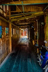Fotobehang Gang Wooden walkway in a small alley with light shining through of Chum Saeng District  © Kobchai M.