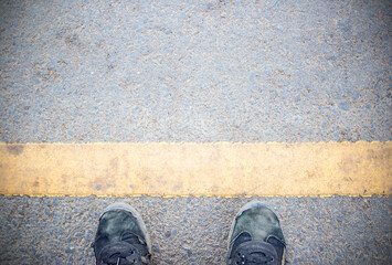 Male feet and old black shoes standing on the concrete floor or street asphalt pavement with...