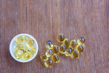 Fototapeta na wymiar Omega 3 fish liver oil capsules in wooden background.