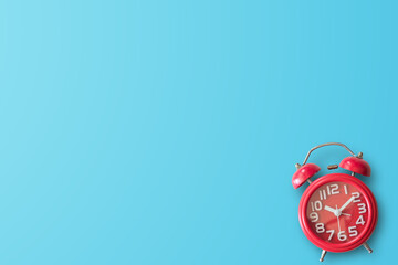 Red alarm clock in studio against blue background with empty place