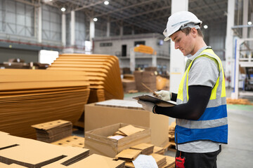 Caucasian foreman or businessman use clipboard checking Kraft paper stock at warehouse	
