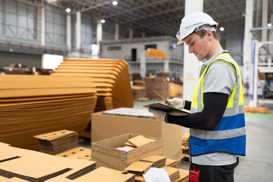 Caucasian foreman or businessman use clipboard checking Kraft paper stock at warehouse