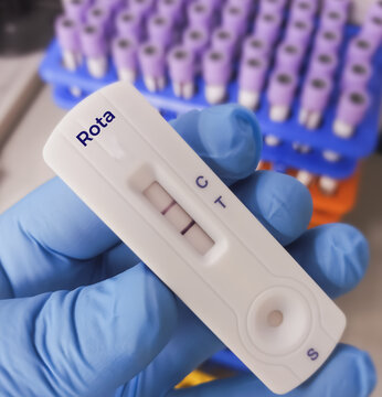 Rapid test device for Rotavirus test showing positive result. Scientist holding Rotavirus infected blood in test tube laboratory background.