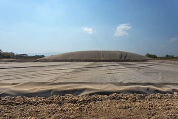 Waste of poultry farm to biogas.  Worker laying thick sheet at the bottom of digester lagoon before...