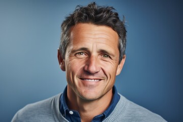 Portrait of a handsome middle-aged man smiling against a blue background