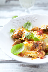 Ravioli with mushrooms and fresh basil. Bright wooden background. Close up.	