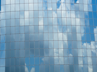Blue sky with clouds reflected in glass windows of skyscraper