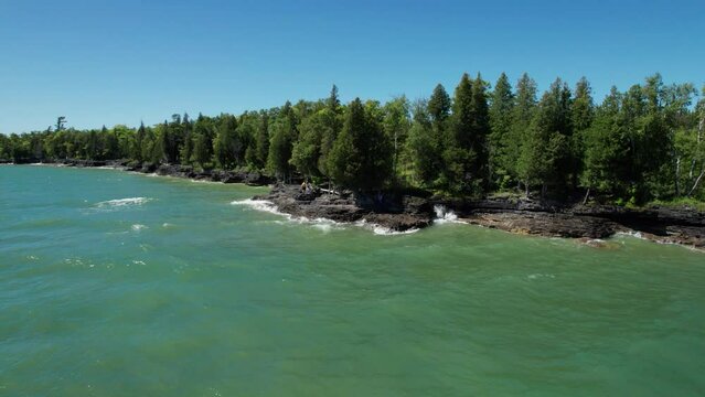 Large waves crash against the rocks of door county on a windy and sunny day