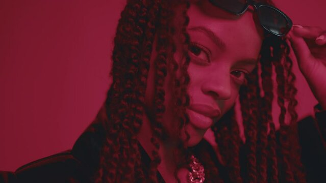 Fashion urban black woman posing with sunglasses in red light interior