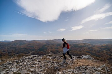 woman on mountain peak looking in beautiful mountain valley in autumn. Landscape with sporty young woman, blu sky in fall. Hiking. Nature