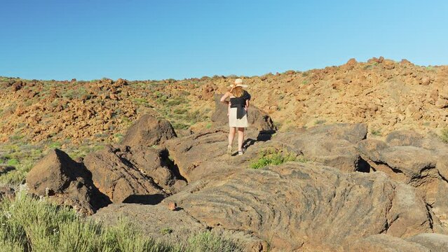 Mother carries baby in ergo carrier while climbing rocks in Teide national park, Tenerife