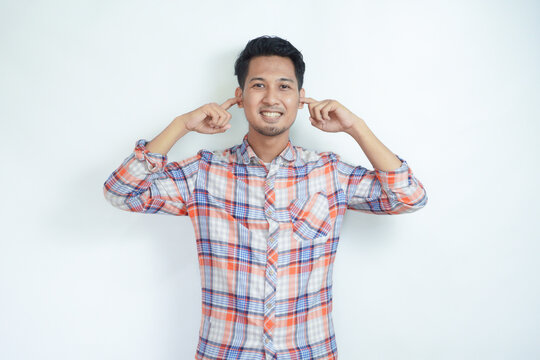 Asian man smiling with open eyes while covering his ears with fingers